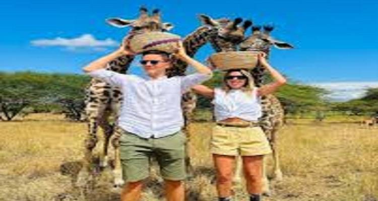 Des gens posant avec des girafes tenant des paniers sur leur tête.