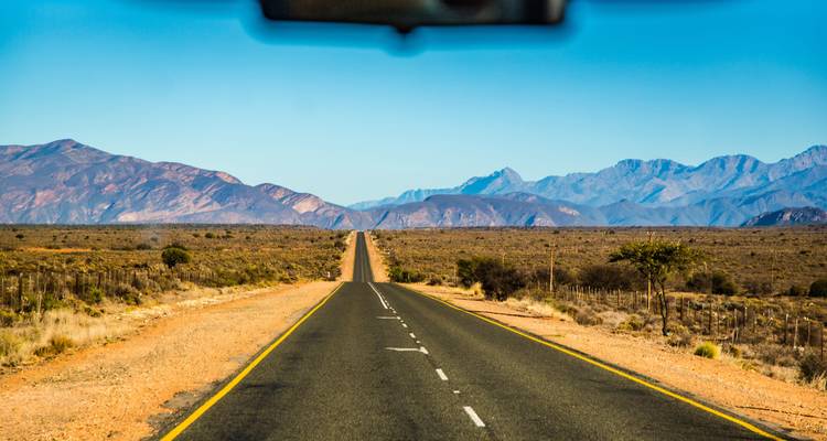 Lange, rechte weg die naar een bergachtig landschap leidt.