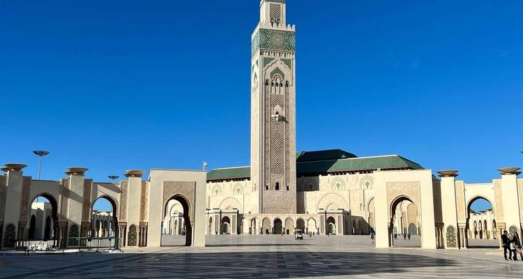 Vaste esplanade de la Mosquée Hassan II à Casablanca sous un ciel bleu éclatant.