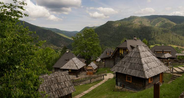 Maisons traditionnelles en bois dans une région montagneuse avec de la verdure.