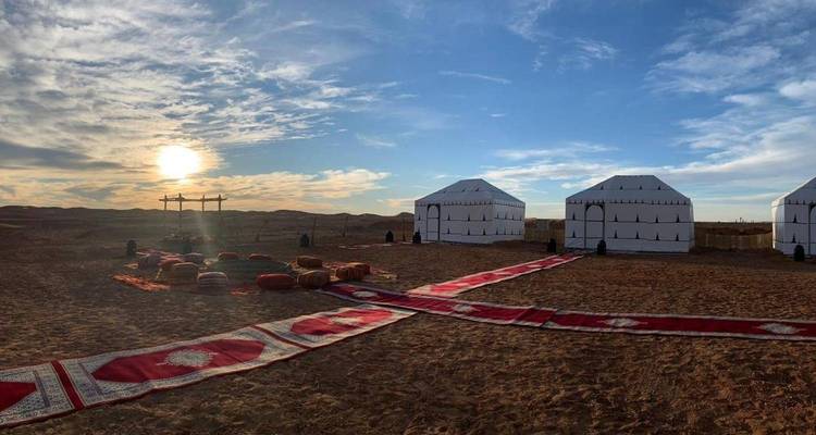Weiße Leinwand-Wüstenzelte mit gemusterten Teppichen ausgekleidet bei Sonnenuntergang in der Sahara nahe Merzouga.