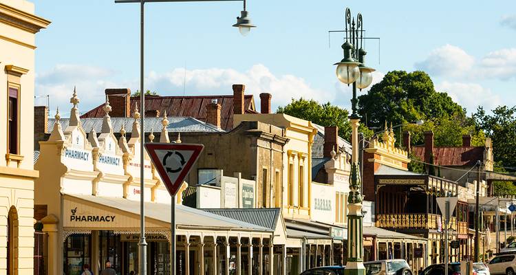 Historical buildings on a sunny day with streetlamps lining the road.