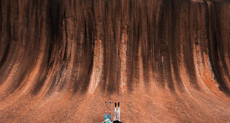 Mensen die staan onder Wave Rock, een opvallende natuurlijke formatie.