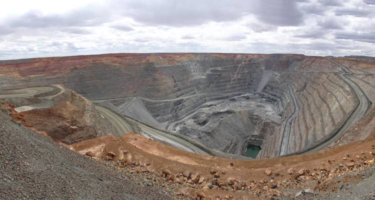 Mine à ciel ouvert profonde avec terre stratifiée et ciel couvert.
