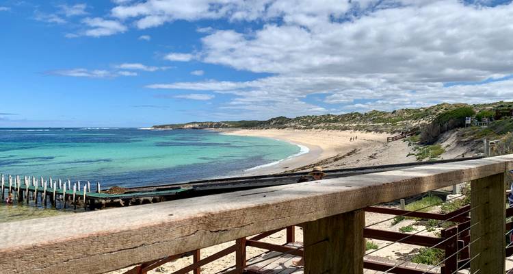 Promenade en bois surplombant une belle plage et l'océan.