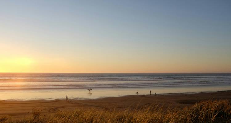 Beach scene at sunset with silhouettes.