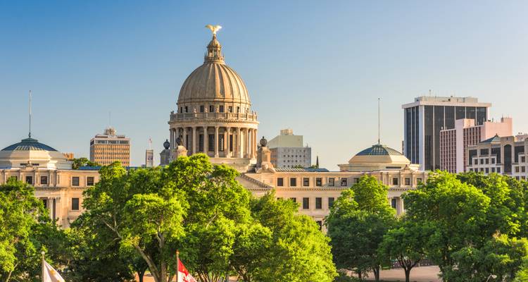 Un grand bâtiment gouvernemental avec un dôme et des arbres qui l'entourent.