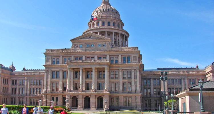 Bâtiment du Capitole avec une pelouse et des touristes qui se promènent.