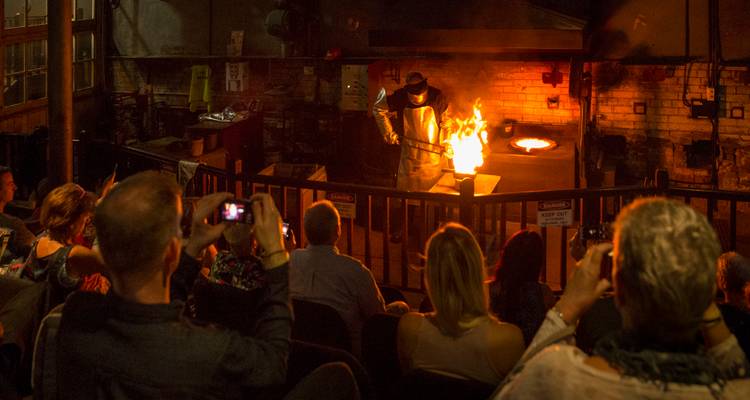 Personas observando una demostración de soplado de vidrio