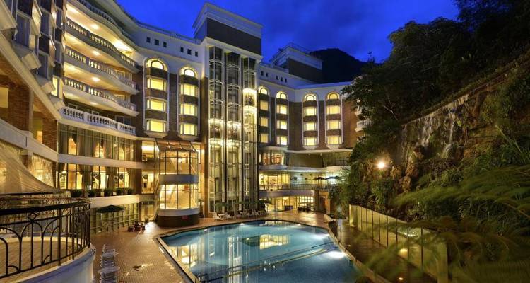 Hôtel luxueux avec une piscine illuminée au crépuscule.