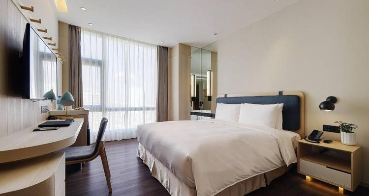 Chambre d'hôtel lumineuse avec design contemporain et grande fenêtre.