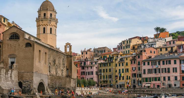 Colorful buildings and a sandy beach with tourists in a coastal town.