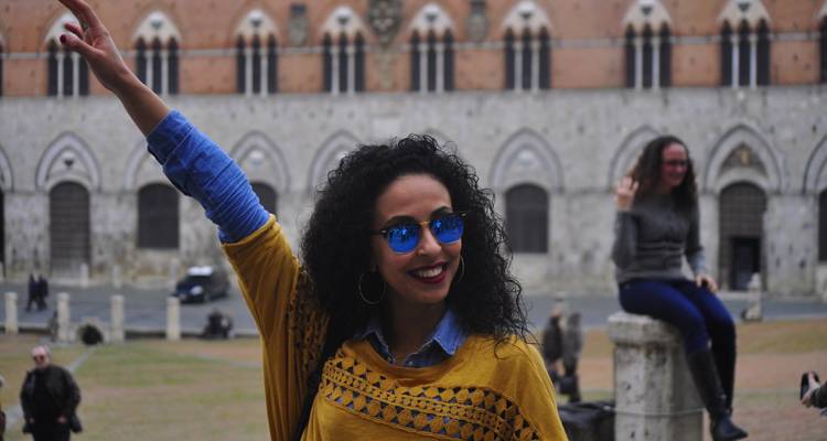A person in sunglasses posing in front of historic buildings.