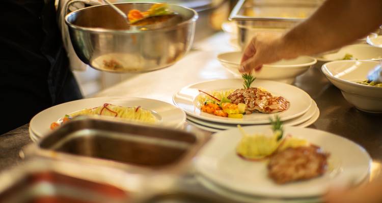 Köche servieren Gourmet-Gerichte in einer belebten Küche an und fügen farbenfrohen Vorspeisen letzte Verfeinerungen hinzu.
