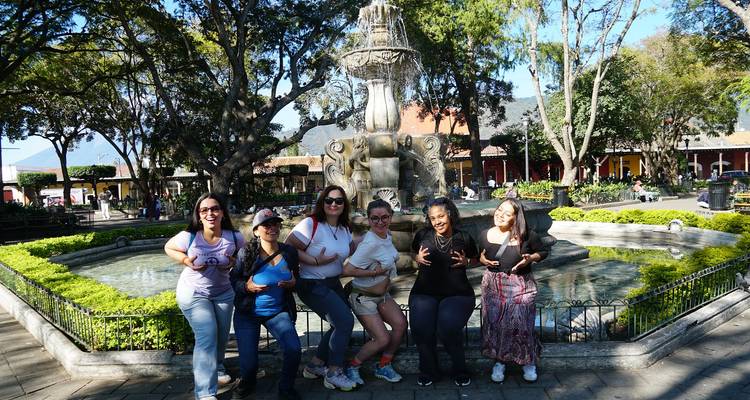 Groep mensen rond een fontein in een parkachtige omgeving.