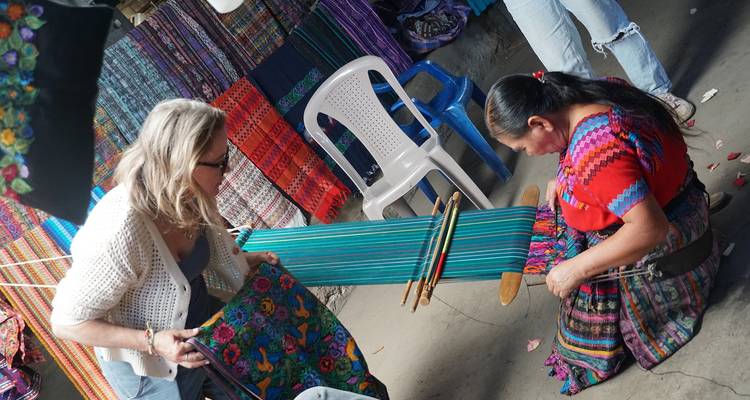 Vrouw die weeft met textiel in een marktomgeving.