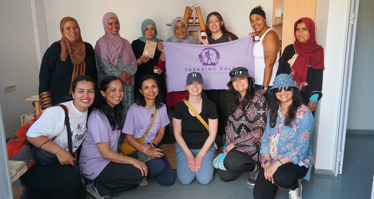 Groupe de femmes posant avec une bannière 'Trekking Pals' à l'intérieur.