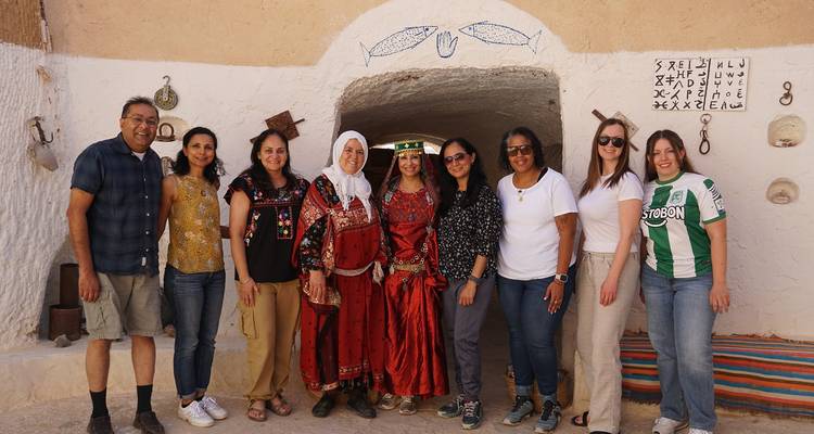 Groupe de personnes debout devant une maison en argile.