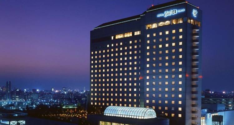 Exterior de un edificio de hotel iluminado por la noche con vista del paisaje urbano.