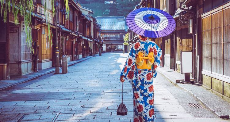 Persona con kimono tradicional caminando por una calle histórica.