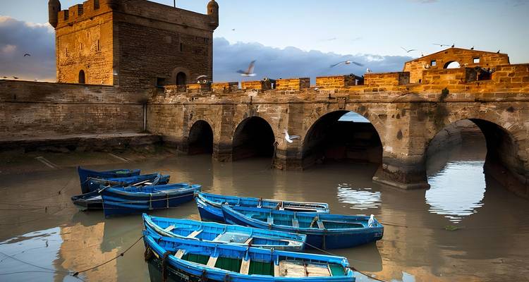 Hafen von Essaouira mit blauen Booten und alten Steinbefestigungen.