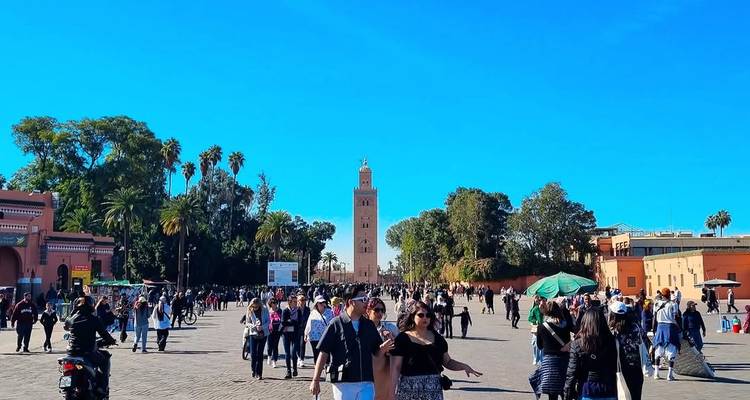 Djemaa el-Fna-Platz in Marrakesch mit Menschen und einem Minarett im Hintergrund.