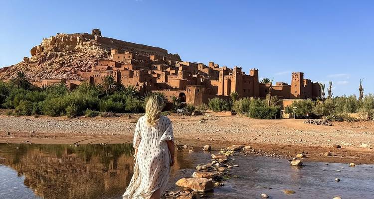 A woman walking towards a historic village amidst a rocky landscape.