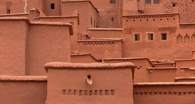 Vista de cerca de edificios de adobe apilados con muros de tierra y ventanas rectangulares en una fortaleza del desierto.