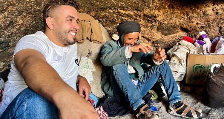 Dos hombres en un entorno rústico compartiendo una conversación.