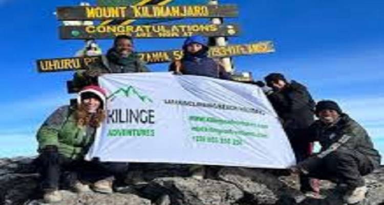 Groupe de grimpeurs avec panneau de sommet et bannière.