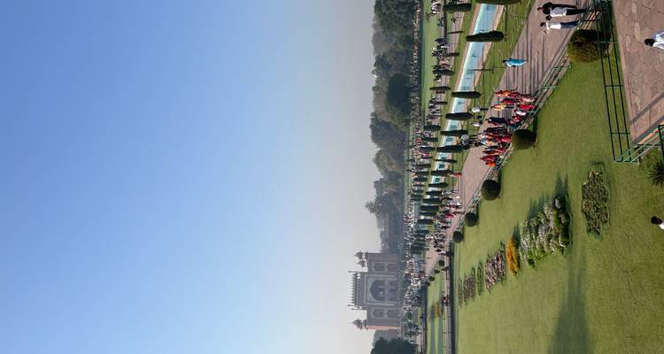 Verhoogd tuinzicht op menigten die over de centrale as naar de poort van de Taj Mahal lopen.