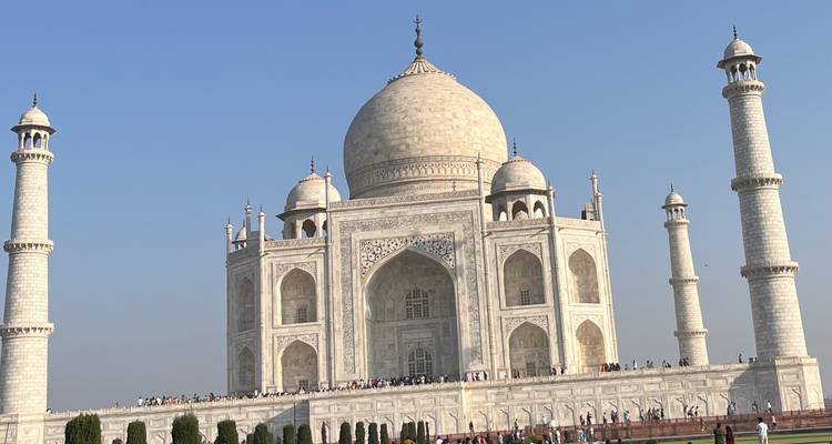 Klassieke frontale aanzicht van de ivooorwitte Taj Mahal met bezoekers langs de plint.