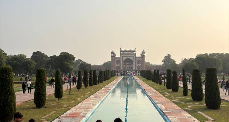 Les visiteurs se promènent le long du long canal d'eau menant à la porte d'entrée du tombeau de Humayun au crépuscule brumeux.