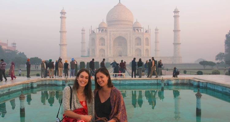 Twee vrienden poseren bij het iconische reflectiebassin met de Taj Mahal die uit de mistige dageraad oprijst