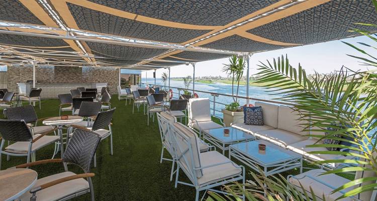 Espace salon extérieur sur le pont d'un navire de croisière avec vue sur une rivière.