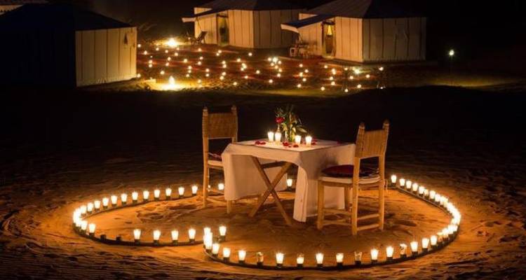 Een romantische dineromgeving bij kaarslicht in de woestijn 's nachts.