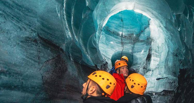 Adventure seekers exploring an icy cave with turquoise formations.