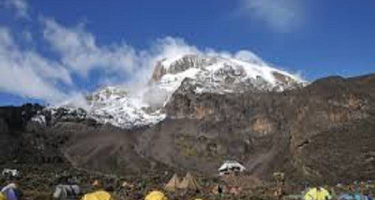 View of Mount Kilimanjaro with snow-capped peaks and tents below.