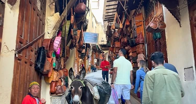 Rue étroite avec des magasins et des gens, âne portant des marchandises.