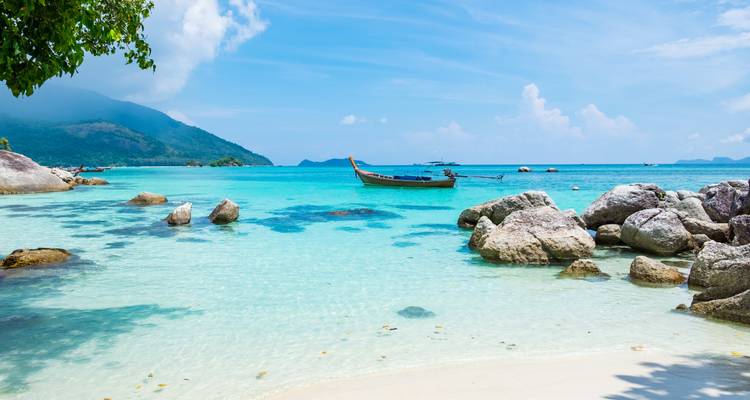 Idyllic beach with clear blue water and a traditional boat.