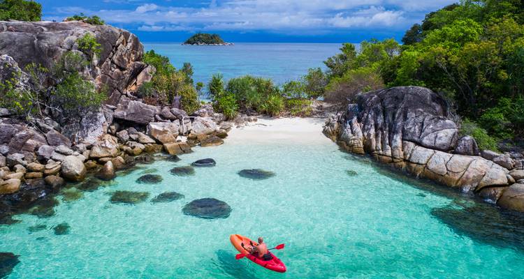 Persoon die kajakken beoefent in een turquoise water baai.