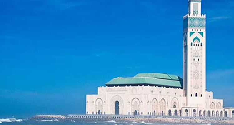 Mosquée Hassan II au bord de l'océan sous un ciel bleu dégagé.