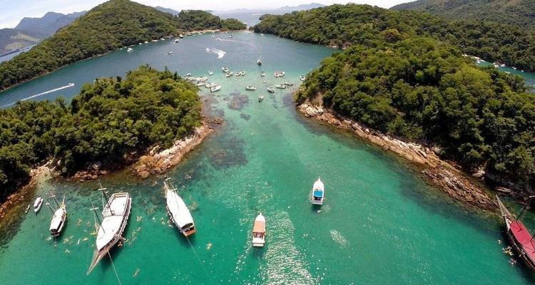 Vue aérienne d'une baie tropicale avec des bateaux et des îles verdoyantes.