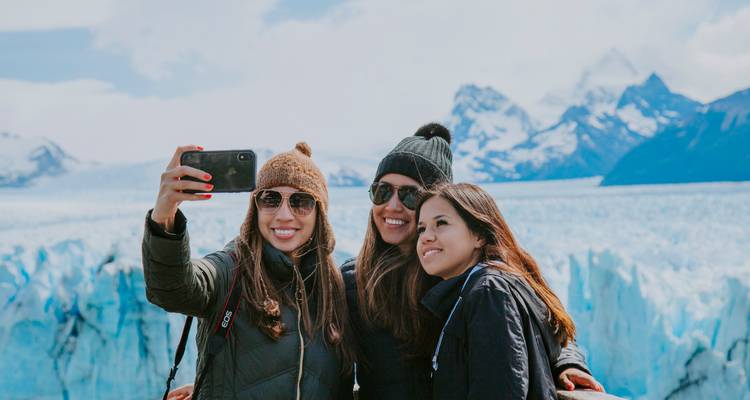 Trois personnes prenant un selfie avec un glacier en arrière-plan.