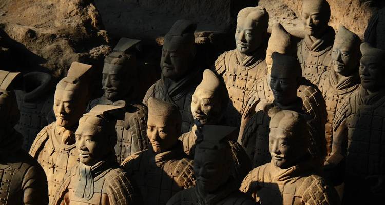 Terracottasoldata figuren dramatisch verlicht met diepe schaduwen die hun gedetailleerde gezichten benadrukken.