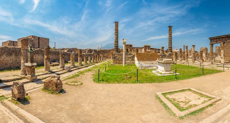Ruinas de Pompeya con columnas y el Monte Vesubio.