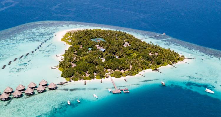 Een luchtfoto van een tropisch eiland met overwater bungalows omringd door helder blauw water.