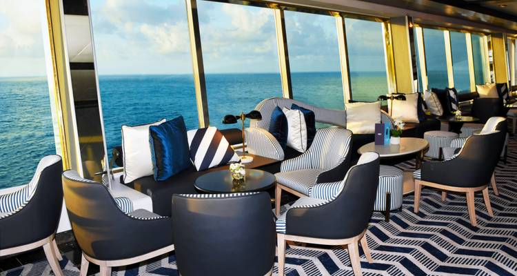 Interieur van een loungeruimte met uitzicht op de oceaan door grote ramen.