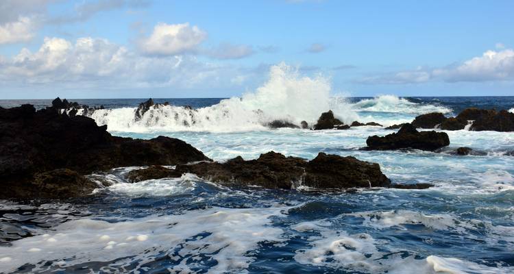 Dramatic ocean waves crashing onto rocky cliffs.