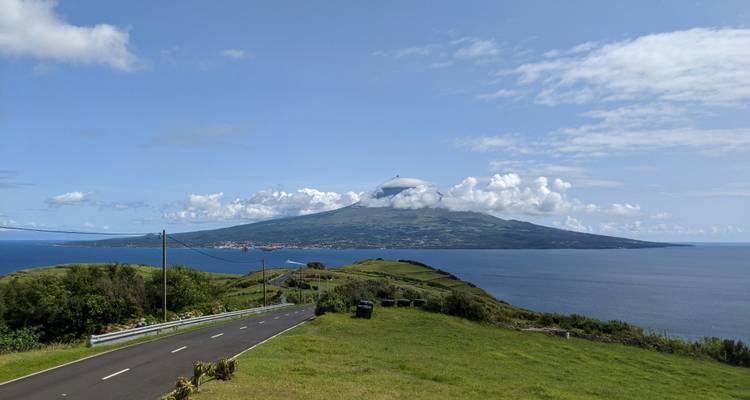 A view of a volcanic island across the sea with a road leading to it.